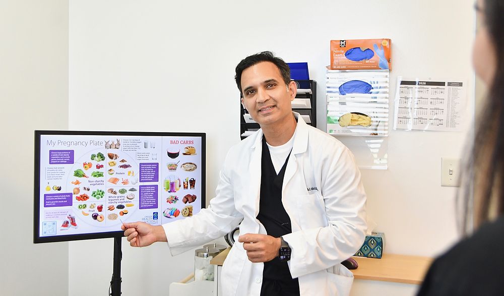 Dr. Malik reviewing pregnancy nutrition with a patient in the exam room